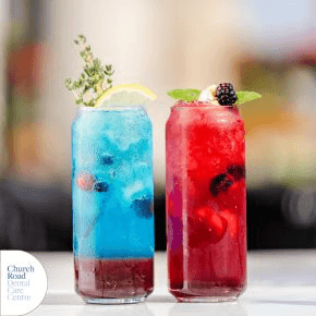 Two glasses containing one red and one blue iced drink with fruits