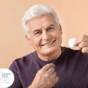 An old man smiling holding a dental floss